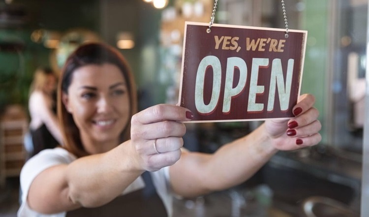 Girl holding We Are Open sign